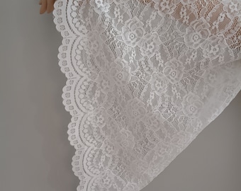 May include: White lace fabric with a scalloped edge. The lace has a floral pattern.
