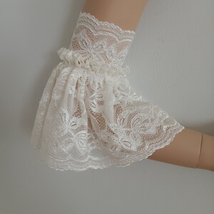 May include: White lace elbow length sleeves with a ruffled edge.