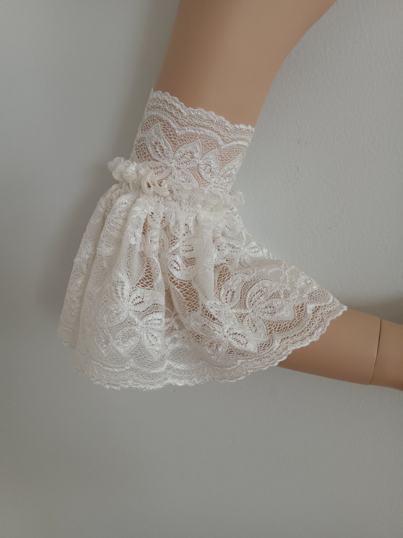 May include: White lace elbow length sleeves with a ruffled edge.