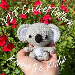 Puede incluir: Un koala gris tejido a ganchillo con una nariz negra y ojos negros pequeños. El koala tiene detalles blancos en las orejas y el pecho. El texto "PDF Crochet Pattern" y "Kenny the Koala" está escrito en escritura cursiva blanca.