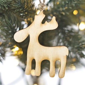 May include: A wooden reindeer ornament in a natural wood color. The ornament is hanging on a Christmas tree.