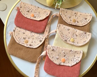 Puede incluir: Cinco pequeñas bolsas de tela con estampados florales y tela de pana. Las bolsas tienen un cierre de solapa con un botón. Las bolsas son de varios colores, incluyendo marrón, beige y rosa.