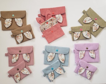 Puede incluir: Nueve pequeñas bolsas de tela con orejas de conejo de estampado floral. Las bolsas son de varios colores, incluyendo marrón, rosa, verde y azul. Cada bolsa tiene un cierre de botón.