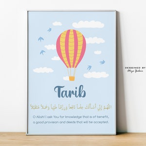 Könnte beinhalten: Ein blaues und weißes druckbares Wandbild mit einem Heißluftballon und Wolken. Der Name "Tarib" ist in blauer Schrift geschrieben. Der arabische Text lautet "Allahumma inni as-aluka ilman nafi'an wa rizqan tayyiban wa 'amalan mutaqabbalan". Der Text übersetzt sich mit "O Allah! Ich bitte dich um nützliches Wissen, guten Lebensunterhalt und akzeptierte Taten."
