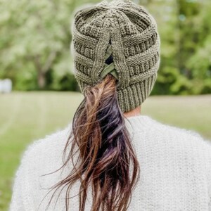 May include: A green knit beanie with a built-in ponytail holder. The beanie is made of a soft, warm material and is perfect for keeping your head and ears warm in the cold weather.