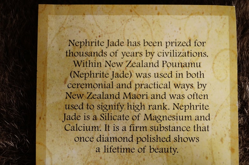 Puede incluir: Primer plano de una tarjeta de color beige con texto marr&oacute;n que describe la historia y las propiedades de la jade&iacute;ta. El texto dice: "La jade&iacute;ta ha sido apreciada durante miles de a&ntilde;os por las civilizaciones. En Nueva Zelanda, el pounamu (jade&iacute;ta) se us&oacute; tanto en ceremonias como en la vida pr&aacute;ctica por los maor&iacute;es de Nueva Zelanda y a menudo se us&oacute; para indicar un rango alto. La jade&iacute;ta es un silicato de magnesio y calcio. Es una sustancia firme que, una vez pulida con diamante, muestra una belleza para toda la vida."