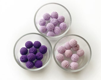 May include: Three glass bowls filled with crocheted purple and lavender balls. The balls are different shades of purple and lavender.