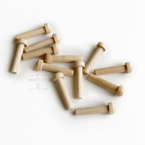 May include: A group of 12 wooden dowels with rounded tops. The dowels are scattered on a white surface.  The dowels are approximately 1.5 inches long.