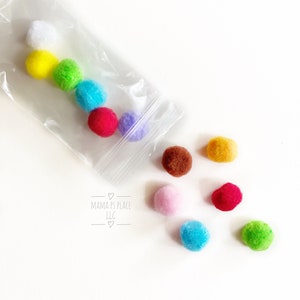 May include: A clear plastic bag filled with colorful pom poms. The bag is open and the pom poms are spilling out. The pom poms are in the colors white, yellow, green, blue, red, purple, brown, orange, pink, light blue, and dark green. The bag has the text "Mama's Place LLC" printed on it.
