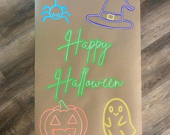 May include: A rectangular brown paper sheet featuring neon-style illustrations and the text Happy Halloween in bright green. The design includes a blue spider, a purple witch hat, an orange jack-o'-lantern, and a yellow ghost graphic.