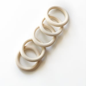 May include: Five unfinished wooden rings stacked on top of each other. The rings are all the same size and shape, and they are made of a light-colored wood.