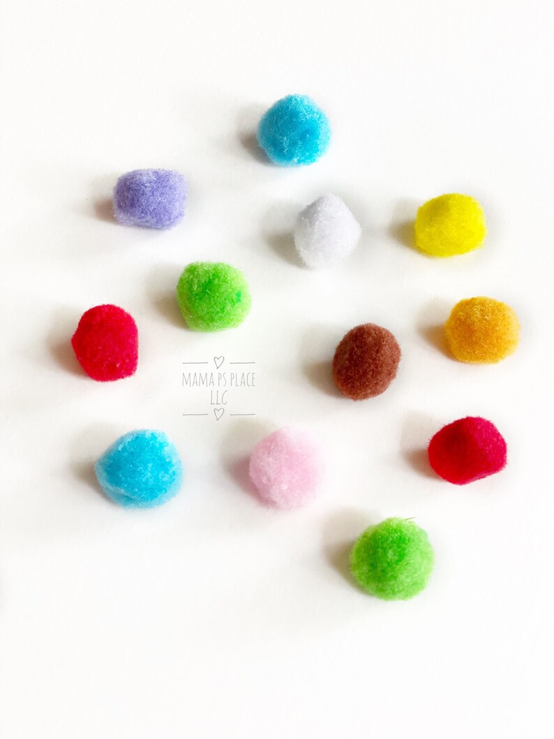 May include: A collection of 10 colorful pom-poms in various colors, including red, blue, green, yellow, purple, pink, white, and brown. The pom-poms are arranged on a white surface.