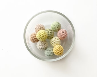 May include: A bowl of crocheted yarn balls in various pastel colors, including pink, yellow, and green.