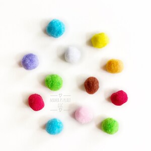 May include: Ten colorful pom-poms in various colors including blue, green, red, yellow, white, purple, brown, and orange. The pom-poms are arranged in a circle on a white background. The text "MAMMA'S PLACE LLC" is written in the center of the circle.