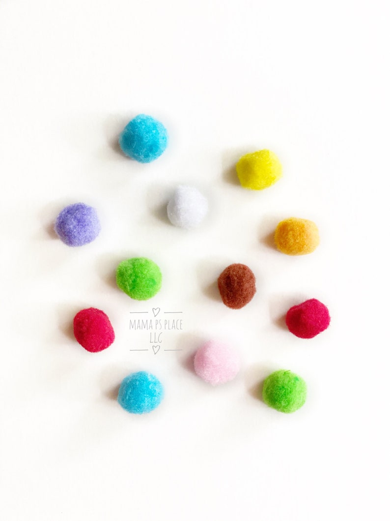May include: Ten colorful pom-poms in various colors including blue, green, red, yellow, white, purple, brown, and orange. The pom-poms are arranged in a circle on a white background. The text "MAMMA'S PLACE LLC" is written in the center of the circle.