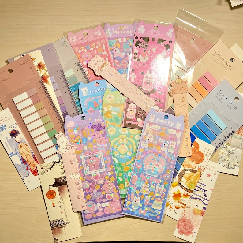 May include: An assortment of colourful stickers and washi tape featuring cute cartoon characters, animals, and designs. The stickers include themes such as "Good Night", "Sea Side", "Daily Chick", and "Party". The washi tape is in various colours and patterns.