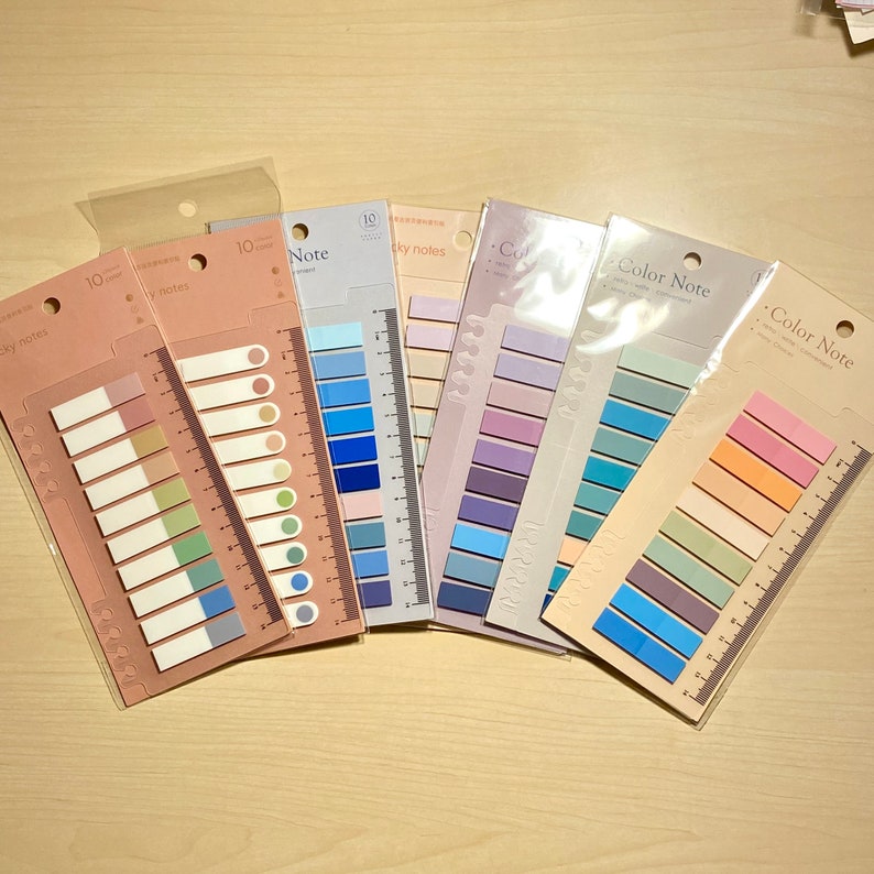 May include: A set of ten colourful sticky note pads with a ruler on the side. The pads are in various shades of blue, purple, green, and orange. The text on the pads reads "Color Note" and "Sky Notes".
