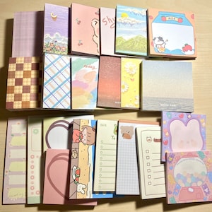 Puede incluir: Una colecci&oacute;n de blocs de notas adhesivas de colores con varios dise&ntilde;os, incluyendo a cuadros, a rayas, florales y personajes de dibujos animados. Los blocs tienen diferentes tama&ntilde;os y formas, y algunos tienen las palabras "hoy", "nota para" y "m&aacute;quina de dulces de amor dulce" impresas en ellos.