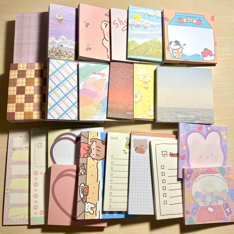 Puede incluir: Una colecci&oacute;n de blocs de notas adhesivas de colores con varios dise&ntilde;os, incluyendo a cuadros, a rayas, florales y personajes de dibujos animados. Los blocs tienen diferentes tama&ntilde;os y formas, y algunos tienen las palabras "hoy", "nota para" y "m&aacute;quina de dulces de amor dulce" impresas en ellos.
