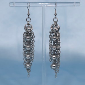 May include: A pair of silver dangle earrings with multiple chain links and round beads.
