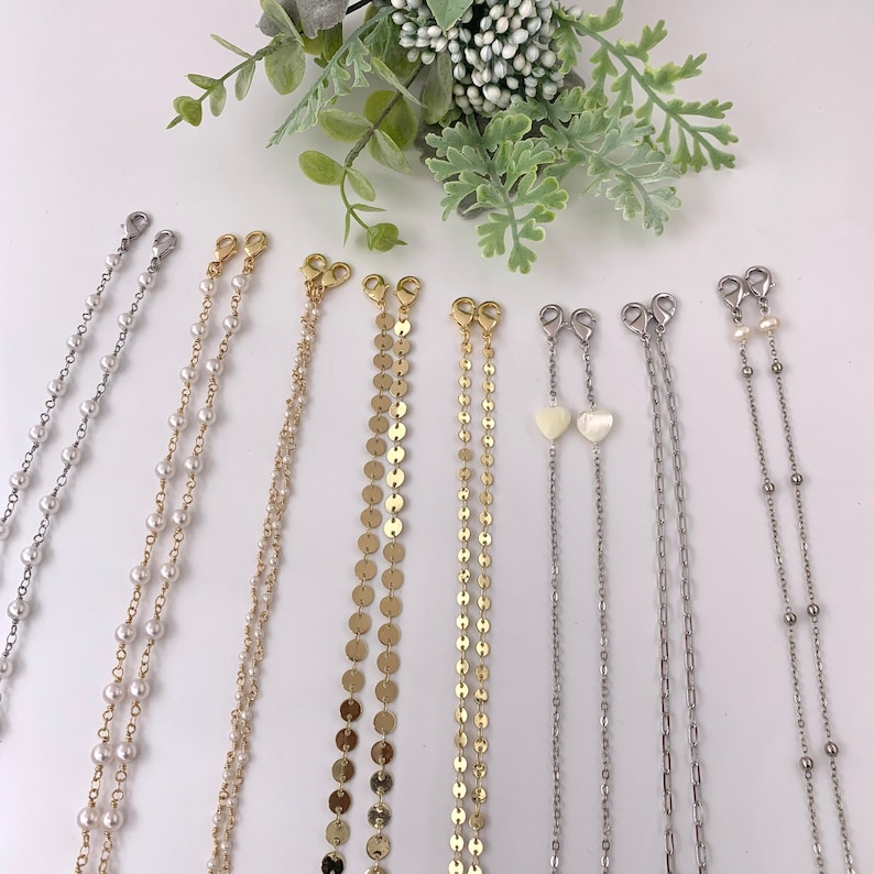 May include: A set of eight gold and silver chain mask extenders. The chains are made of different materials, including pearls, beads, and metal discs. Some chains have a heart-shaped charm.