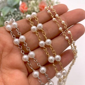 May include: Three strands of pearl necklaces with different chain styles. The top strand has a gold chain, the middle strand has a silver chain, and the bottom strand has a silver chain with a gold accent.
