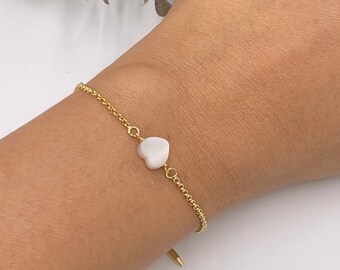 May include: A delicate gold chain bracelet with a small white heart charm.