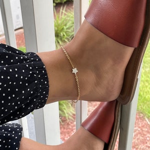 May include: A gold chain ankle bracelet with a small white star charm.