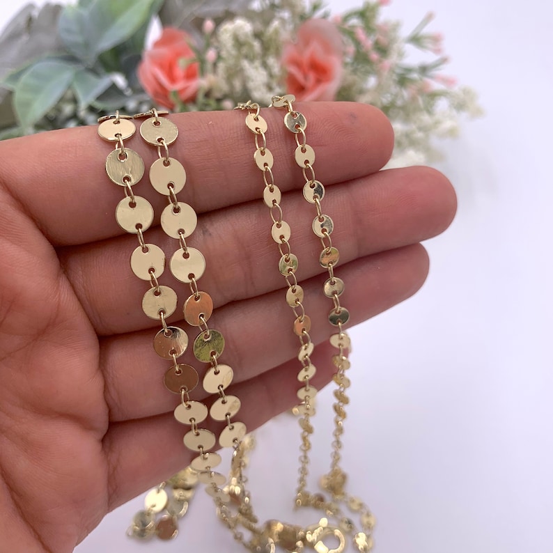 May include: Three gold chains with round, flat links. The chains are different lengths and the links are different sizes.