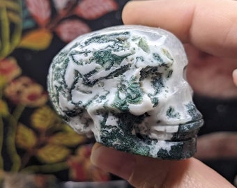 May include: A green and white agate skull carving. The skull is polished and has a detailed design.