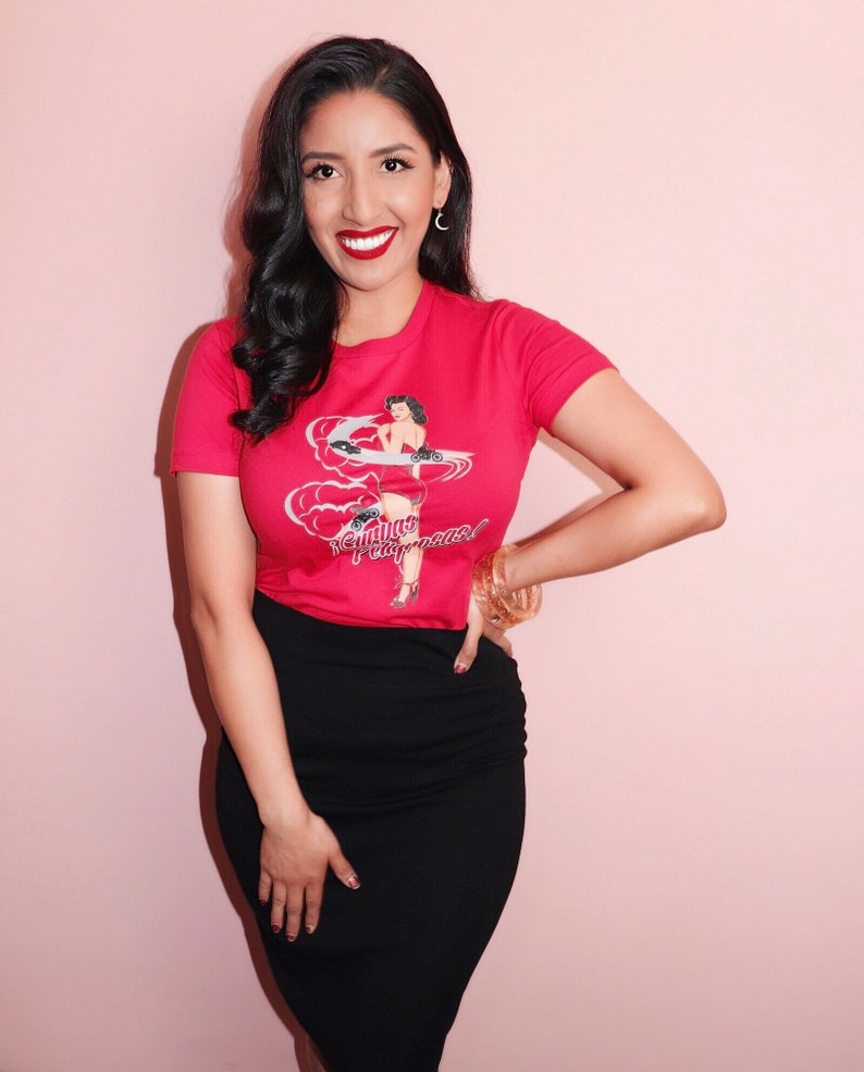 K&ouml;nnte beinhalten: Eine Frau tr&auml;gt ein rotes T-Shirt mit einem Vintage-Pin-up-Girl-Motiv und dem Text "California Dreamin'" und einen schwarzen Bleistiftrock.