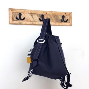 Les bretelles du sac à dos sont réglables par l’intermédiaire de boucles coulissantes, afin de s’adapter parfaitement à l’enfant. Le verso des bretelles est en polaire marine, ce qui les rend confortables et agréables à porter pour le tout-petit.