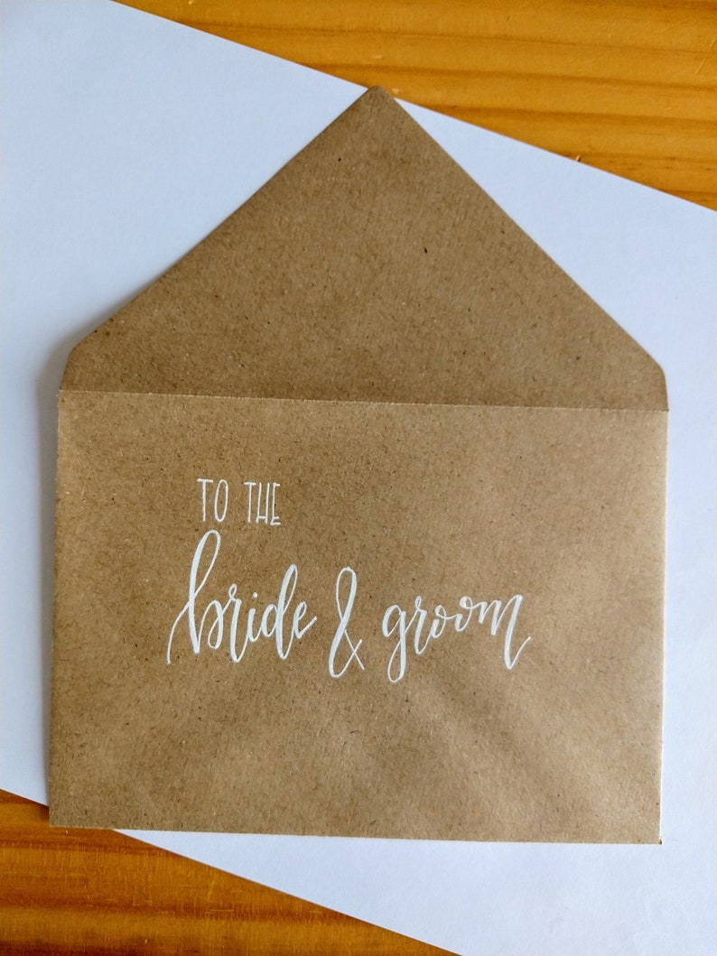May include: A brown paper envelope with the words "To the bride & groom" written in white calligraphy.