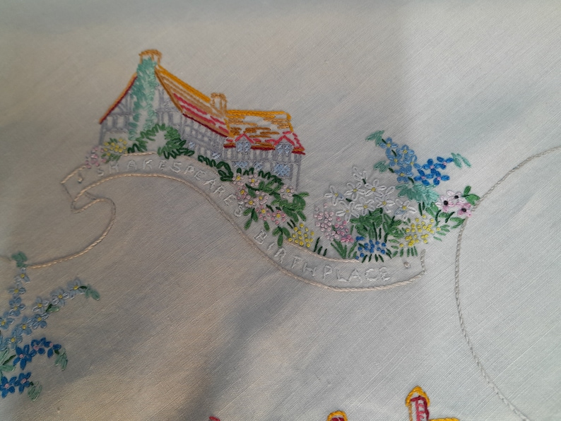 May include: Embroidered white linen tablecloth with a colorful floral design and the text "Shakespeare's Bath Place".