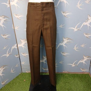 May include: A pair of solid dark brown trousers featuring a high-waisted design, a front zip fly closure, and a structured waistband with belt loops. The trousers have a straight-leg cut with a clean, pressed crease running down the centre of each leg.