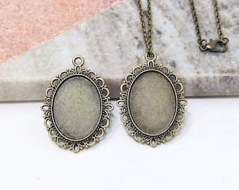 May include: Two antique gold oval pendant trays with a decorative filigree border. The larger tray is on a chain necklace.