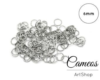 May include: A pile of silver-colored 6mm jump rings. The image includes the text "Cameos ArtShop". These small, circular rings are used for jewelry making and crafting.