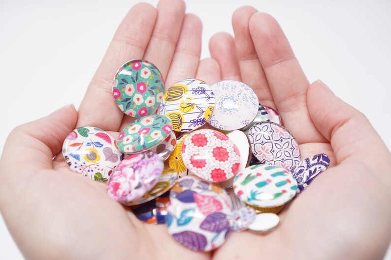Puede incluir: Una colecci&oacute;n de cabujones redondos de vidrio de colores con varios patrones florales y geom&eacute;tricos. Los cabujones tienen un di&aacute;metro de aproximadamente 2,5 cm y son perfectos para proyectos de manualidades.