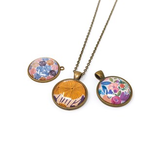 Puede incluir: Tres colgantes redondos con diferentes dise&ntilde;os de patrones. Los colgantes est&aacute;n hechos de metal con un acabado bronce. Los patrones incluyen un dise&ntilde;o floral, un dise&ntilde;o geom&eacute;trico y un dise&ntilde;o con peque&ntilde;os c&iacute;rculos. Los colgantes est&aacute;n en un collar de cadena.