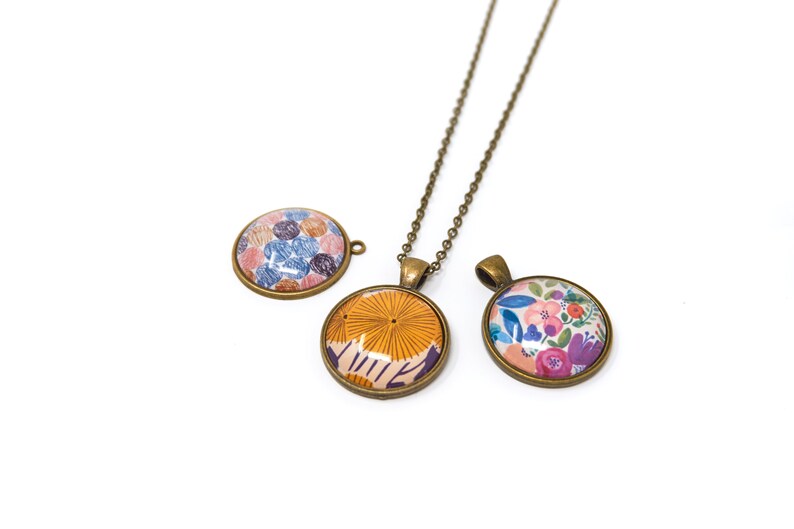 Puede incluir: Tres colgantes redondos con diferentes dise&ntilde;os de patrones. Los colgantes est&aacute;n hechos de metal con un acabado bronce. Los patrones incluyen un dise&ntilde;o floral, un dise&ntilde;o geom&eacute;trico y un dise&ntilde;o con peque&ntilde;os c&iacute;rculos. Los colgantes est&aacute;n en un collar de cadena.