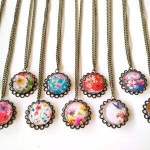 Puede incluir: Diez collares con cadenas de bronce y colgantes redondos de vidrio con motivos florales coloridos. Cada colgante est&aacute; enmarcado con un borde decorativo de bronce.