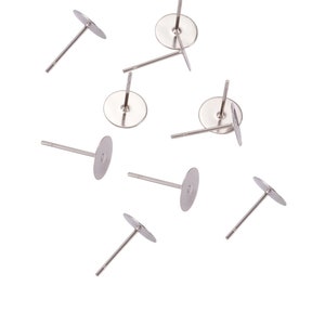 May include: Eight silver earring posts with flat round backs. The posts are scattered on a white background.