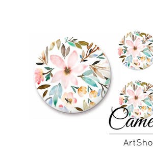 Op de afbeelding: Drie ronde, witte keramische onderzetters met een aquarel bloemenontwerp. Het ontwerp bevat roze, witte en gele bloemen met groene bladeren op een witte achtergrond.