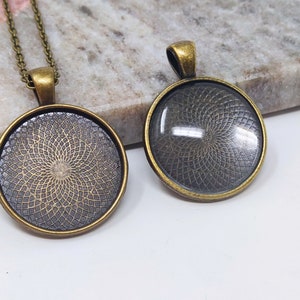 May include: Two antique gold-toned pendant necklace settings with a circular glass insert. The glass insert has a geometric pattern.