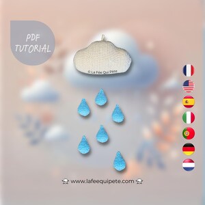 May include: A white crocheted cloud with blue crocheted raindrops hanging below. The text "La Fee Qui Pete" is visible on the cloud. The text "www.lafeequipete.com" is visible below the cloud.