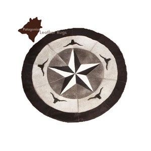 Può includere: Un tappeto rotondo in pelle marrone con una stella bianca a cinque punte al centro. La stella è circondata da un anello di pelle marrone con quattro corna di bue stilizzate. Il tappeto ha un bordo nero. Il testo "Patagonia Leather Rugs" è visibile nell'angolo in alto a destra dell'immagine.
