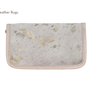 May include: A white leather clutch with gold accents. The clutch has a light pink border and a zipper closure.