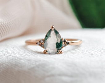 Op de afbeelding: Een ring in peer-vorm met een groene mosagaat edelsteen en kleine diamanten gezet in een gouden band.
