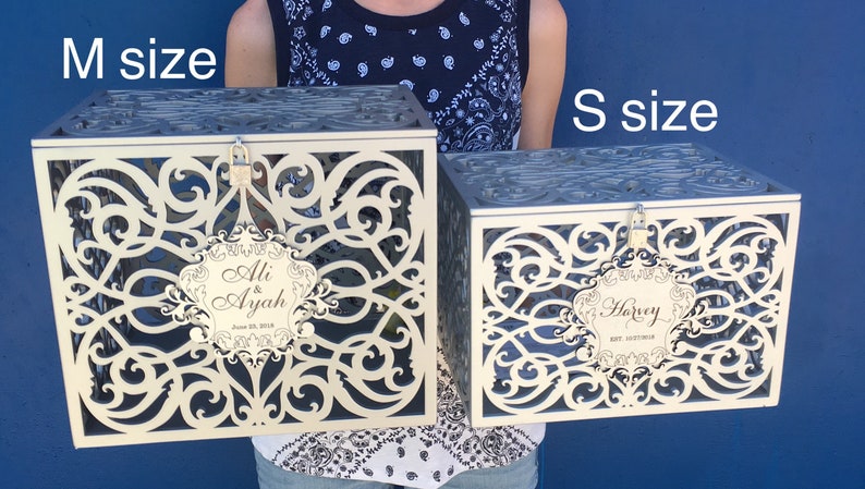 May include: Two decorative wedding card boxes, one labeled "Ali & Ayah" and the other "Harvey", in different sizes. The larger box is labeled "M size" and the smaller box is labeled "S size".