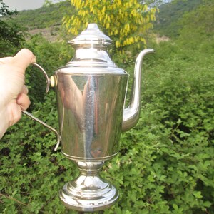 May include: A silver teapot with a rounded body and a curved spout. The teapot has a polished finish and a decorative handle.